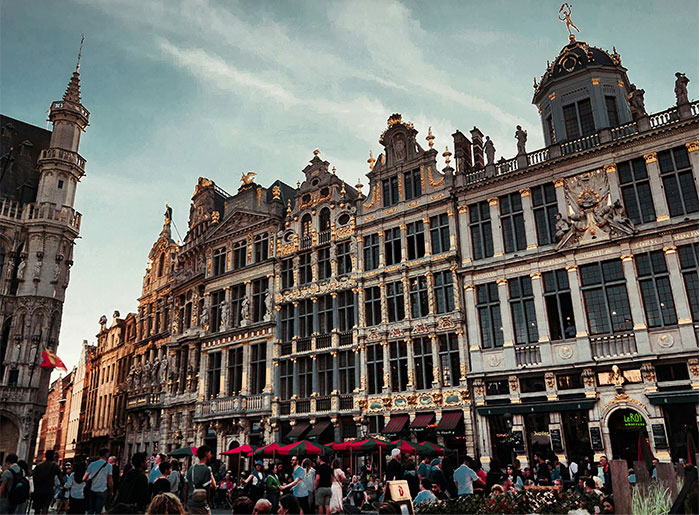 Grand Place buildings in Brussels, crowded with tourists under a clear sky.