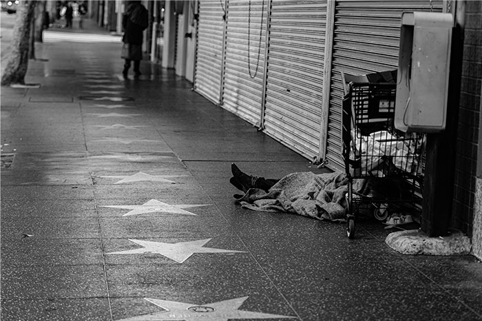 Hollywood Walk of Fame sidewalk, stars visible, with a street cart and person lying down.