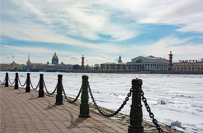 Frozen river view with historical buildings, iron chains along the promenade in a hyped travel destination.