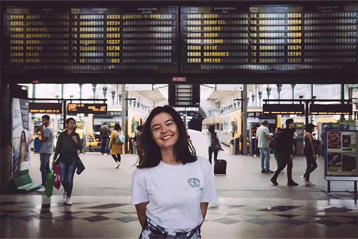 Smiling woman in front of train station schedule board, a popular travel destination.
