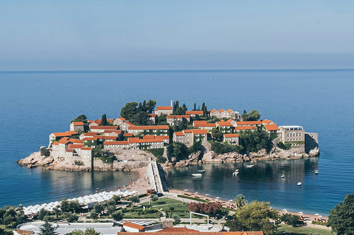 Scenic view of a coastal travel destination with red-roofed buildings on a small island.