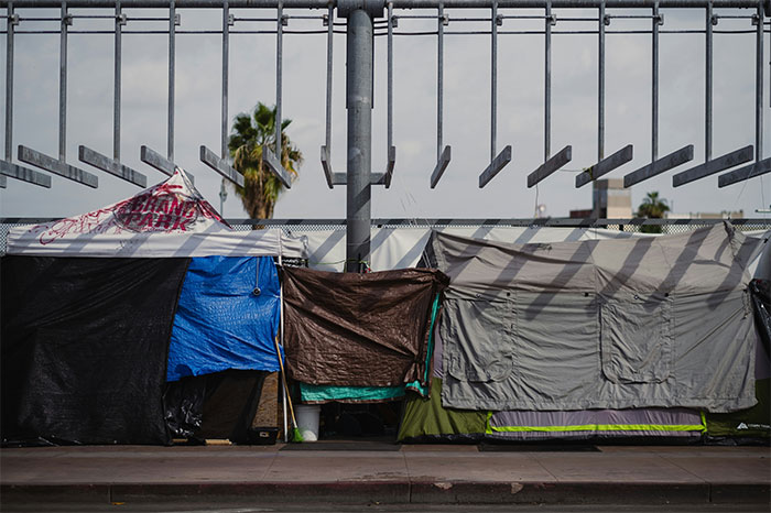 Tents set up along a street in a city, under a cloudy sky, highlighting overhyped travel destination disappointment.