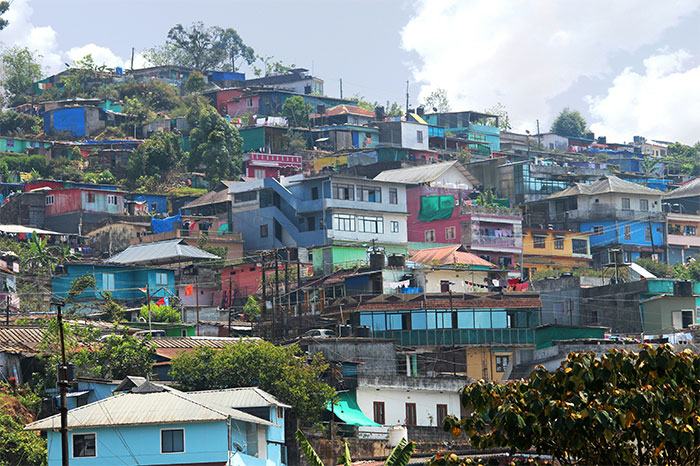 Colorful hillside community overlooked as a travel destination, covered in vibrant houses under a partly cloudy sky.