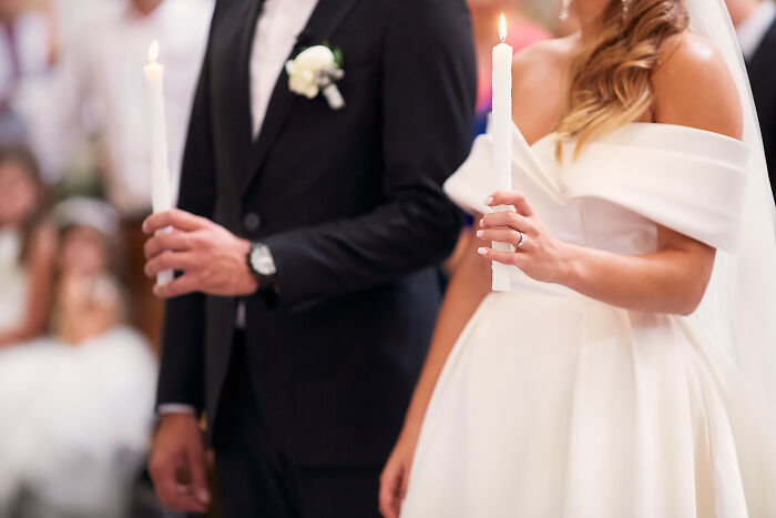 Bride and groom holding candles during a wedding ceremony.