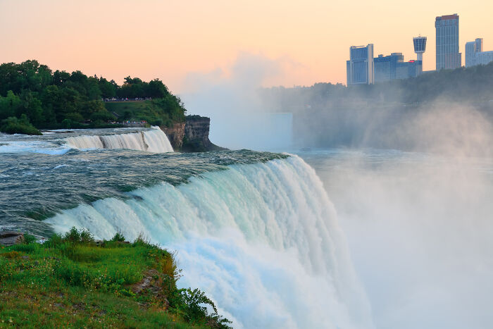 Waterfall cascading with city skyline in background during sunset, emphasizing the theme of "no dumb questions."