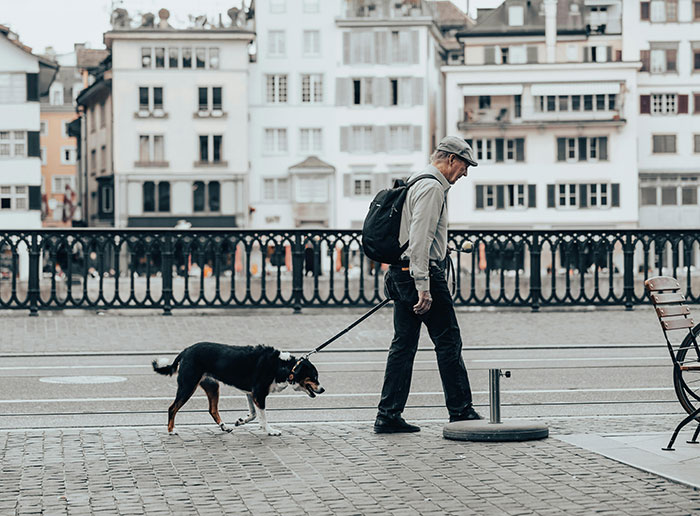 Senior man walking his dog on a city street, illustrating senior life experiences in an urban setting.