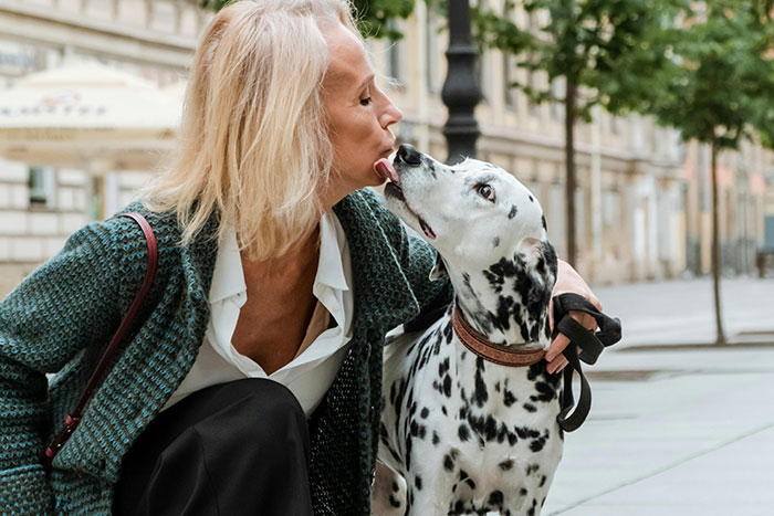 Senior woman and Dalmatian sharing a moment outside, illustrating connections for those who are totally alone.