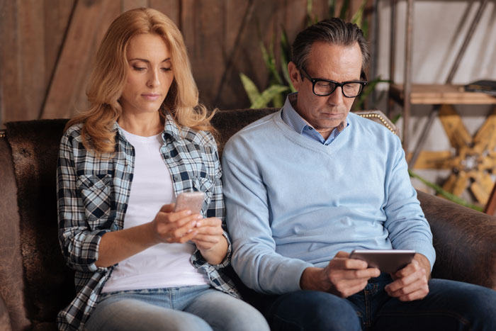 Parents focused on their devices, possibly concerned about their child's date activities. Parents focused on their devices, possibly concerned about their child's date activities.