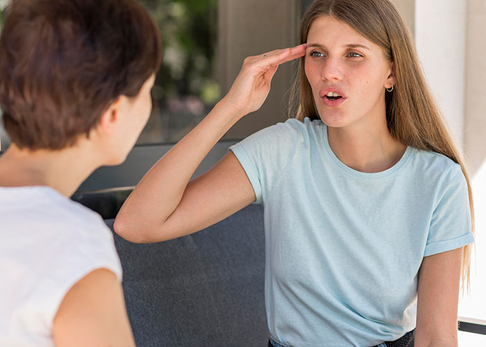 Two women in a discussion, one gesturing, highlighting harsh life realities.