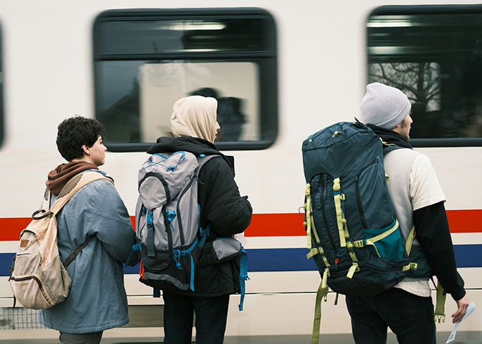 Young adults with backpacks standing near a moving train, symbolizing life realities faced in their 20s.
