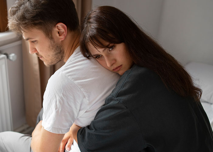 A young woman embraces a man, looking thoughtful, representing harsh life realities faced in their 20s.