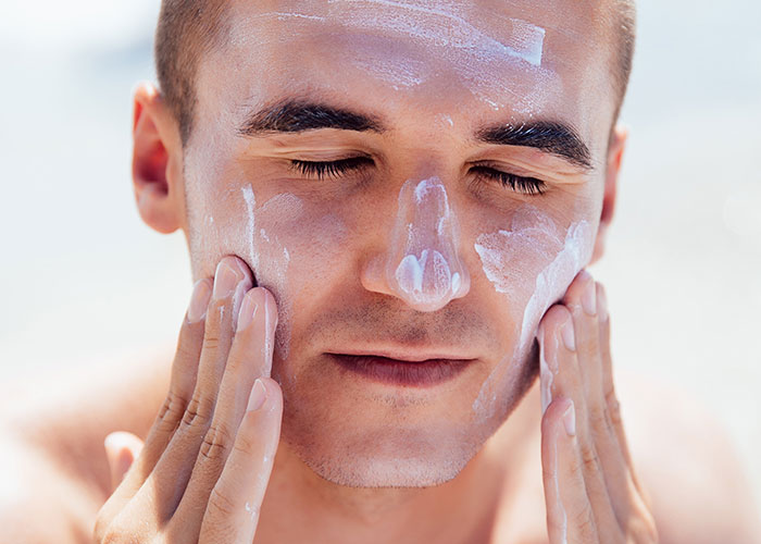 Man applying sunscreen, illustrating harsh life realities awareness for 20-somethings.