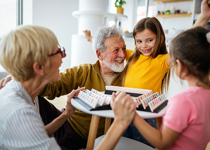 Older adults and kids playing a board game, depicting harsh life realities discussion and wisdom sharing across generations.