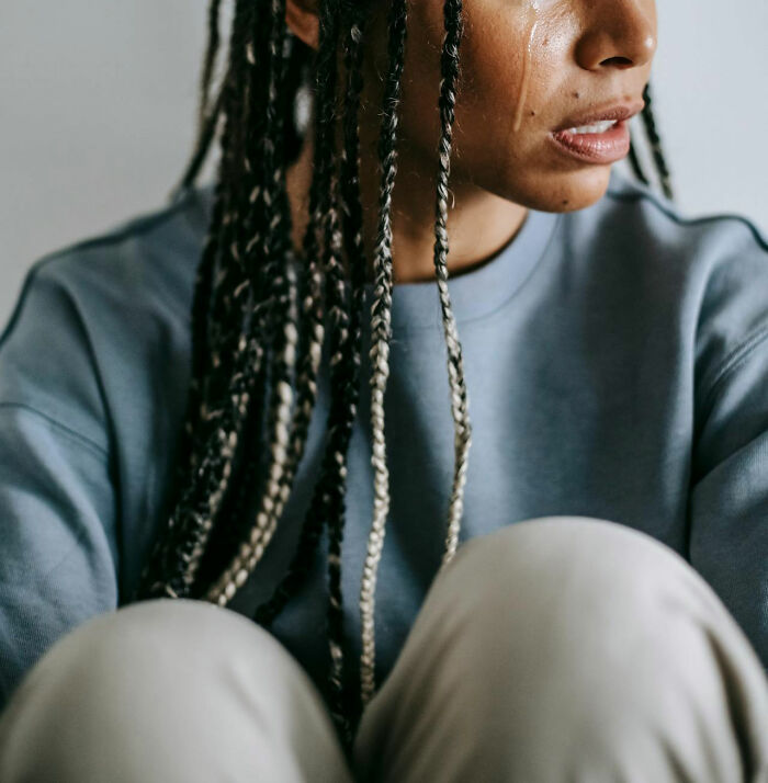 A person with braids and a thoughtful expression, reflecting on family-secrets.