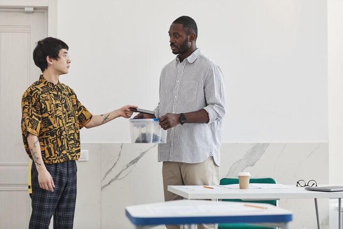 Two people in a discussion, holding a container, in a casual office setting, highlighting outnumbered dynamics.