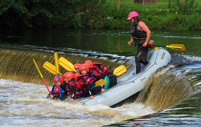 People rafting over a small waterfall, illustrating adventurous decisions and risks in a fun outdoor setting.