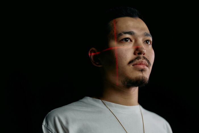 Man in white shirt with red laser crosshairs on face, illustrating conspiracy theories in a dramatic setting.