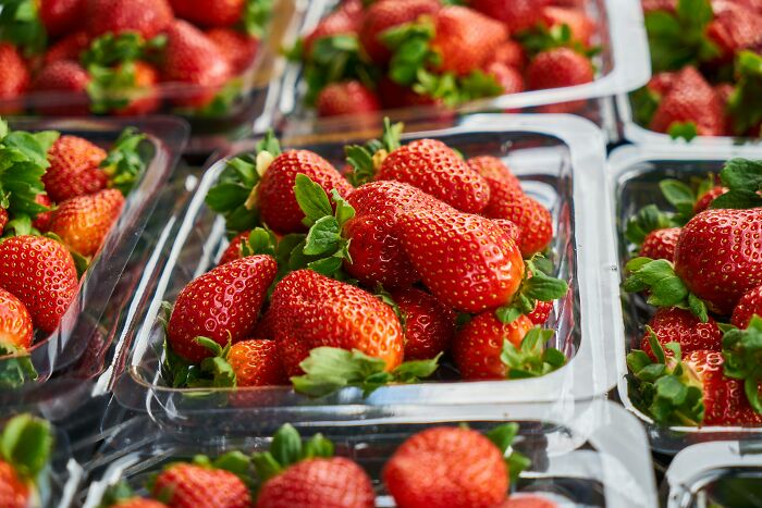 Fresh strawberries in plastic containers, showcasing vibrant colors.