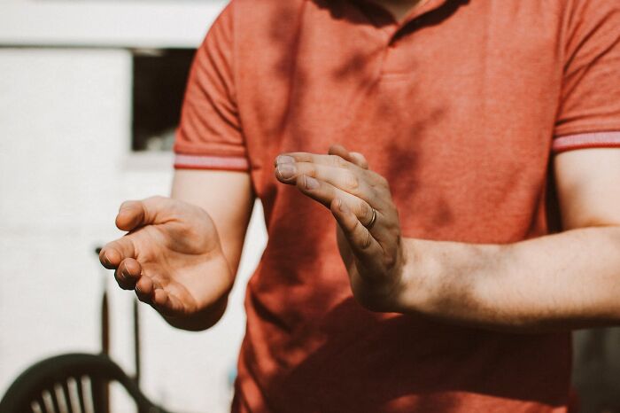 Person in a red shirt gesturing with hands, suggesting group dynamics and decision-making.