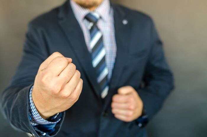 Man in a suit showing a clenched fist symbolizing anger and conflict in toxic relationships and red flags.