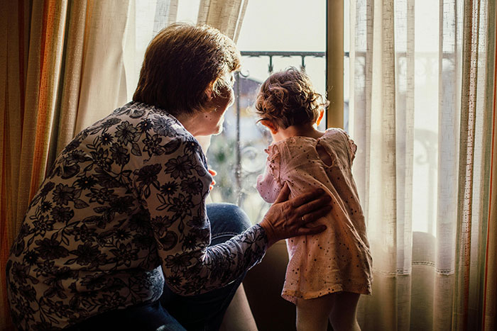 Grandparent with toddler by the window, emphasizing family connection and storytelling. Grandparent with toddler by the window, emphasizing family connection and storytelling.