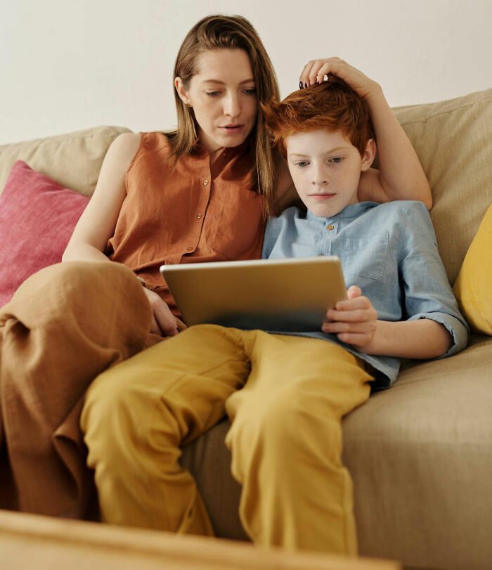 Mother and child on a sofa, discovering family-secrets together on a tablet.