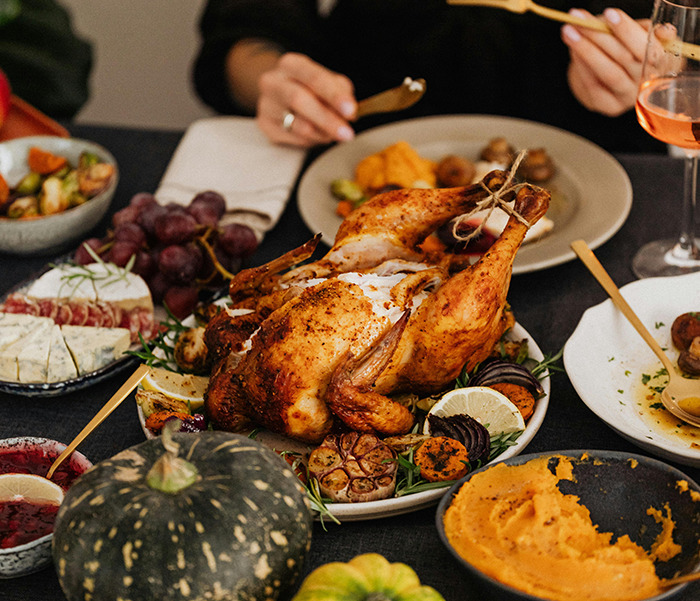 Thanksgiving turkey surrounded by side dishes on a festive dinner table.