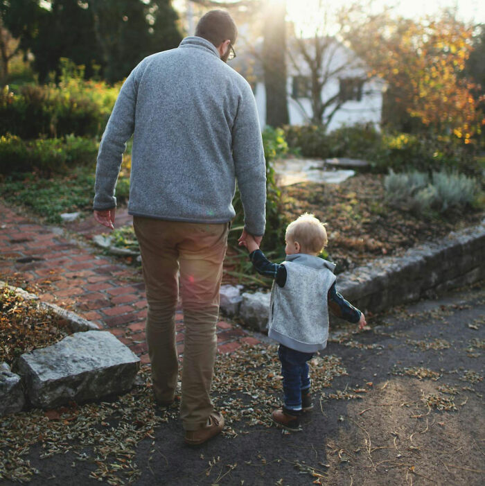 Father and child walking through a garden, symbolizing family-secrets in a serene setting.