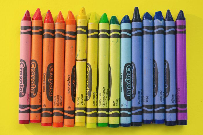 Colorful Crayola crayons neatly arranged on a bright yellow background.