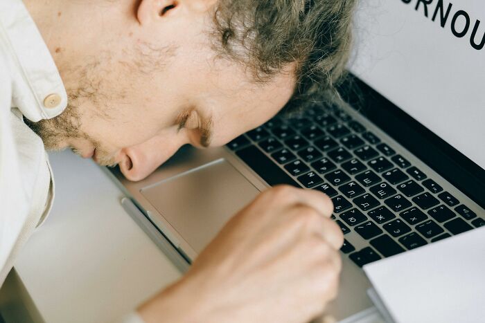 Person leaning on laptop labeled "burnout," illustrating stress and potential bodily harm.