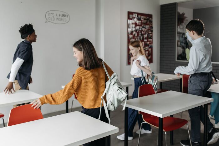 Group of students in a classroom moving desks, emphasizing group dynamics and outnumbering in decision-making.