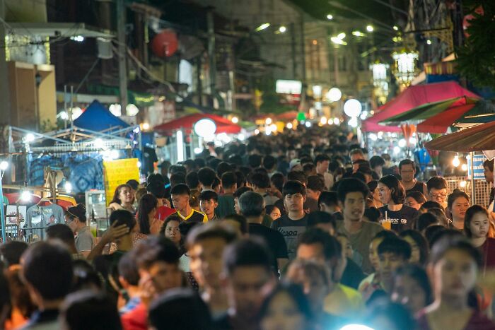 Crowded night market scene, bustling with people and vibrant stalls, linked to conspiracy theories discussions online.