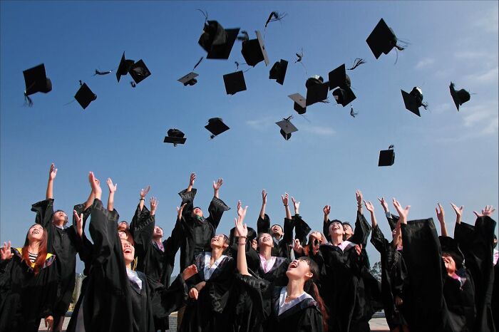 Graduates in black gowns throw caps in the air, illustrating the power of numbers in a jubilant celebration.
