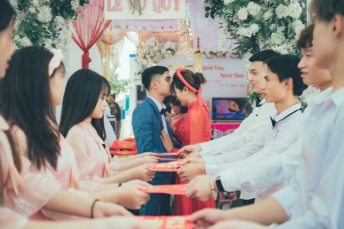 Couple at a wedding ceremony surrounded by bridesmaids and groomsmen in traditional attire.