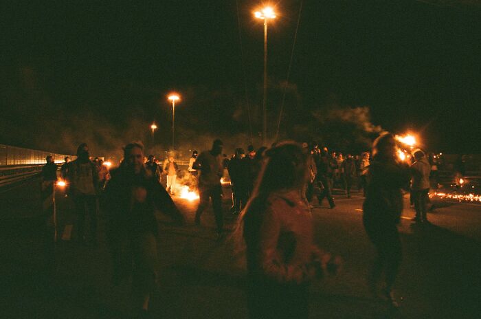 People gathered at night with torches, creating an atmosphere associated with conspiracy theories.