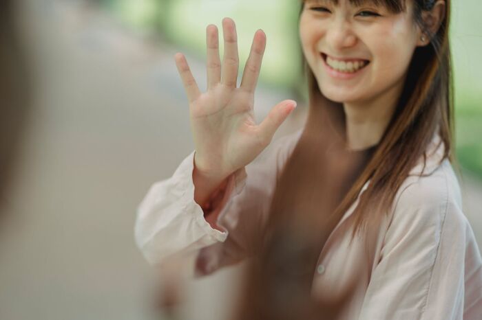 Smiling woman raising her hand in a stop gesture, symbolizing warning signs in toxic relationships and red flags awareness.