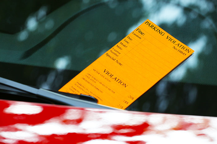 Parking violation ticket on a car windshield, highlighting improper use of handicapped spots by an officer.