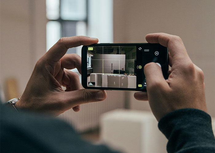 Person photographing a condo interior with a smartphone camera. Person photographing a condo interior with a smartphone camera.