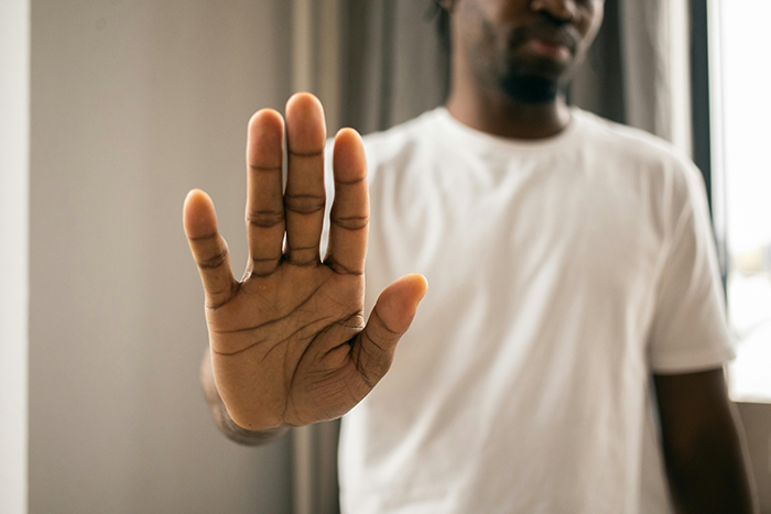 Man in a white shirt holding up his hand in refusal, symbolizing sibling disagreement over babysitting. Man in a white shirt holding up his hand in refusal, symbolizing sibling disagreement over babysitting.