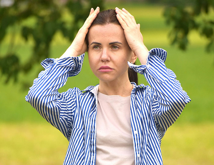 Woman in a striped shirt looking concerned outdoors, related to neighbor's private pond incident lawsuit.