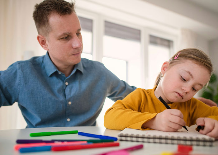 Man watches child drawing with markers, reflecting on kids' behavior near a private pond.