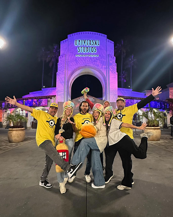 A group of people, including Sydney Sweeney and Jonathan Davino, pose excitedly in front of the illuminated Universal Studios Hollywood entrance at night. They are dressed in yellow Minion-themed attire, some wearing Minion hats and others in Minion shirts, showing playful expressions and energetic poses, celebrating their visit to the theme park. A group of people, including Sydney Sweeney and Jonathan Davino, pose excitedly in front of the illuminated Universal Studios Hollywood entrance at night. They are dressed in yellow Minion-themed attire, some wearing Minion hats and others in Minion shirts, showing playful expressions and energetic poses, celebrating their visit to the theme park.