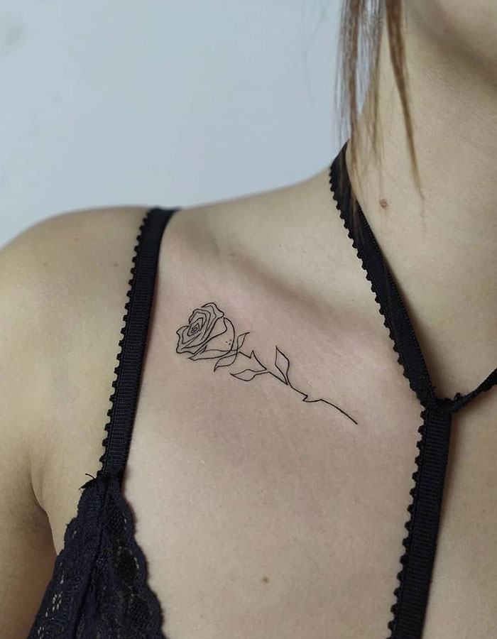 Rose tattoo on a woman's collarbone, featuring delicate line work for a subtle yet daring design.