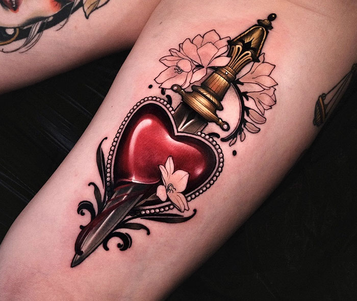 Tattoo design for women featuring a dagger piercing a heart with floral accents.