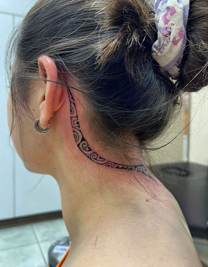 Woman with a subtle ear and neck tattoo design, showcasing a daring style.