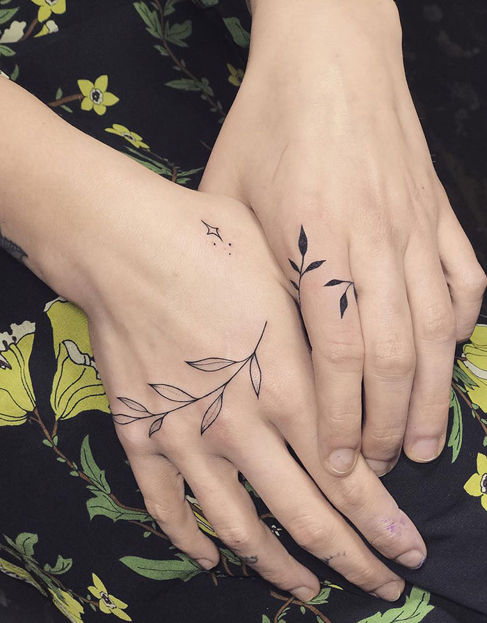 Women's hand tattoos featuring delicate leaf designs on each hand.