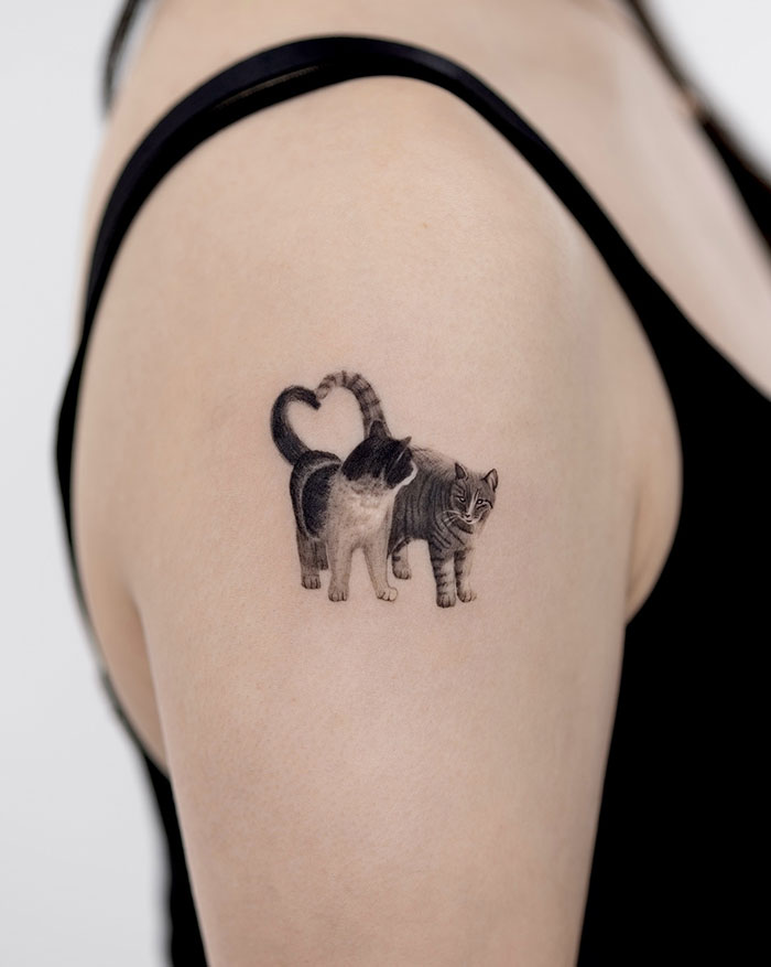 Cat tattoo on woman's shoulder, showcasing daring and subtle design elements.