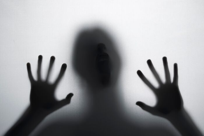 Shadowy figure pressing against frosted glass, representing spine-chilling conspiracy theories.