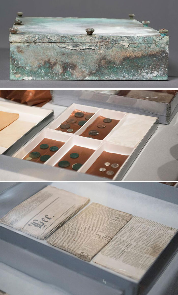 Historical time capsules containing coins and newspapers displayed in protective cases.