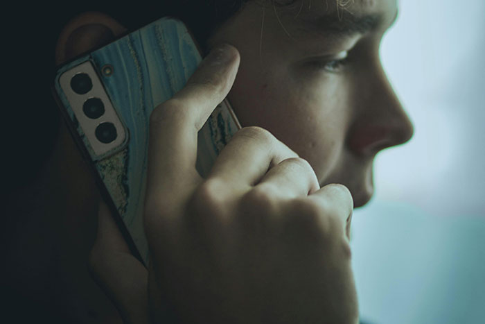Teen on a call, holding smartphone, captures youthful moments and emotions.